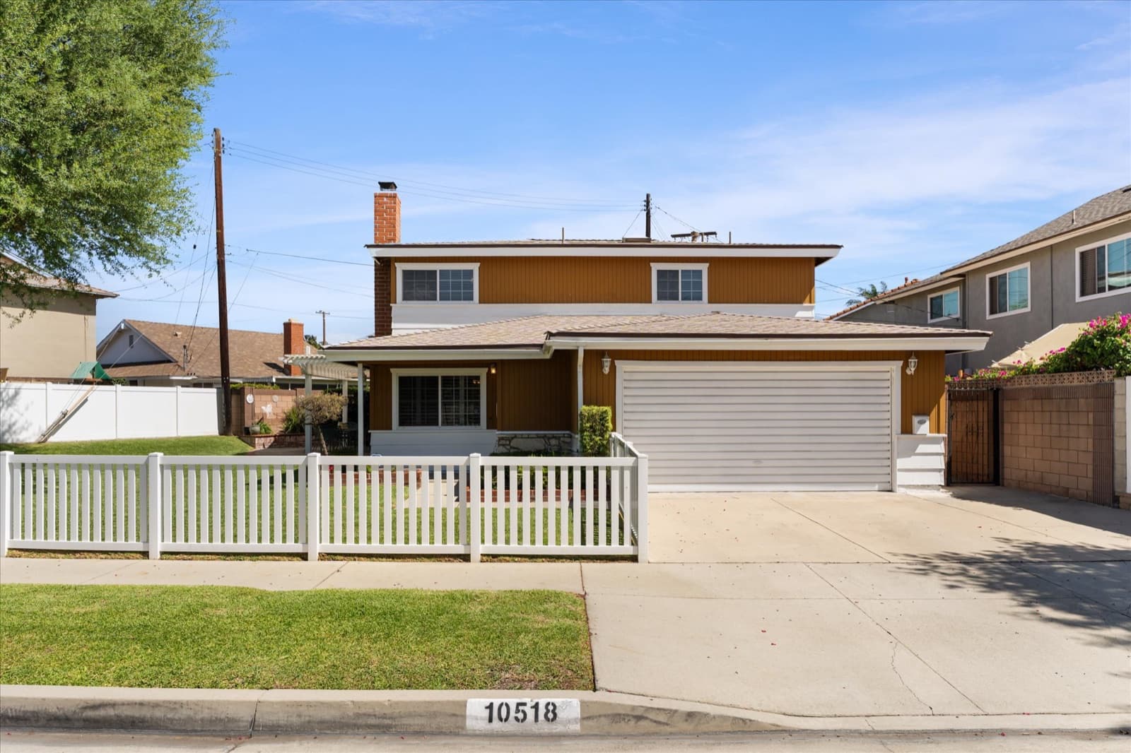 Front exterior of a two-story single-family home with a white fence in South Whittier