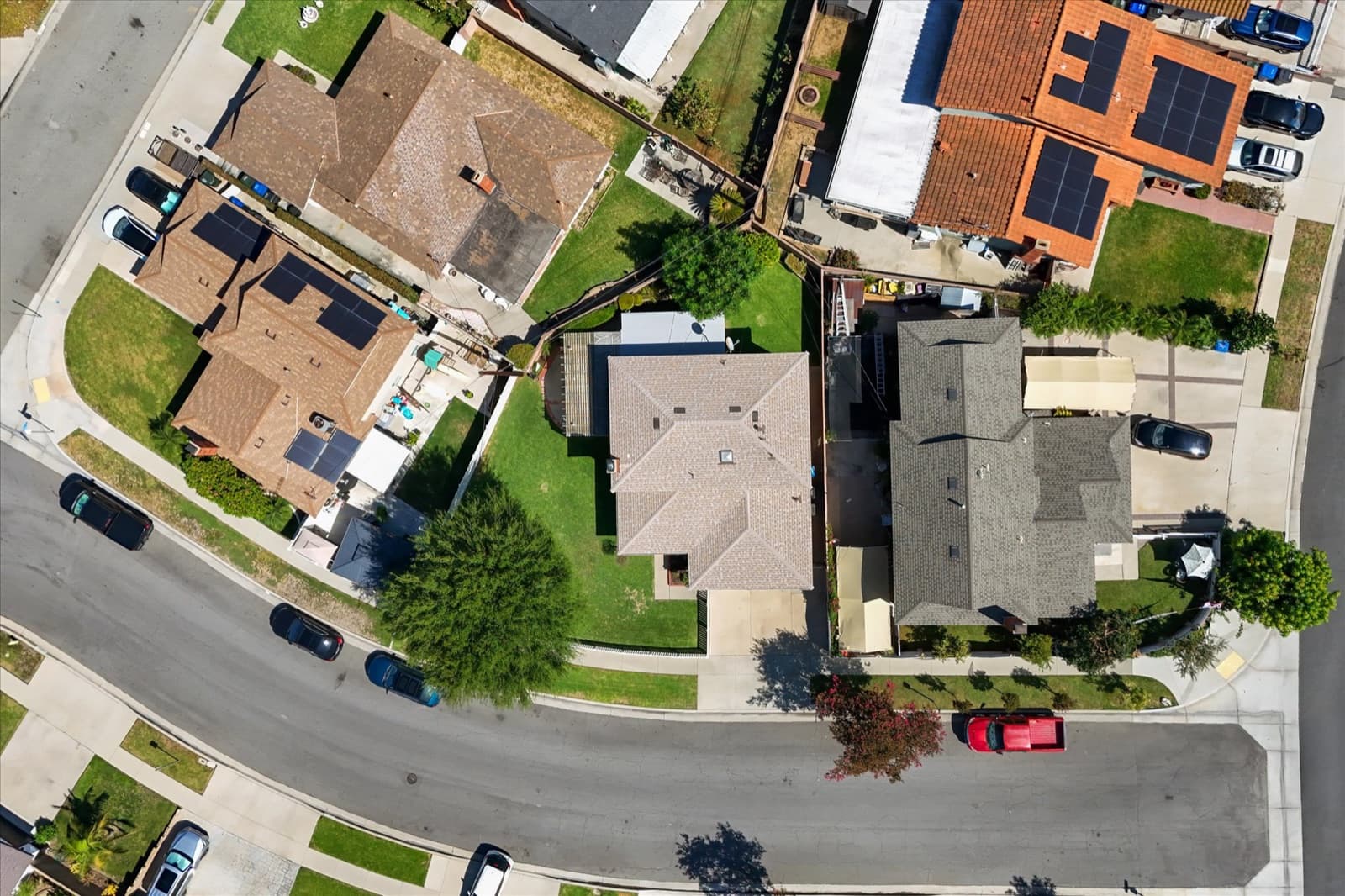 Top-down aerial view of the property showing the roof, driveway, backyard lawn, and adjacent lots