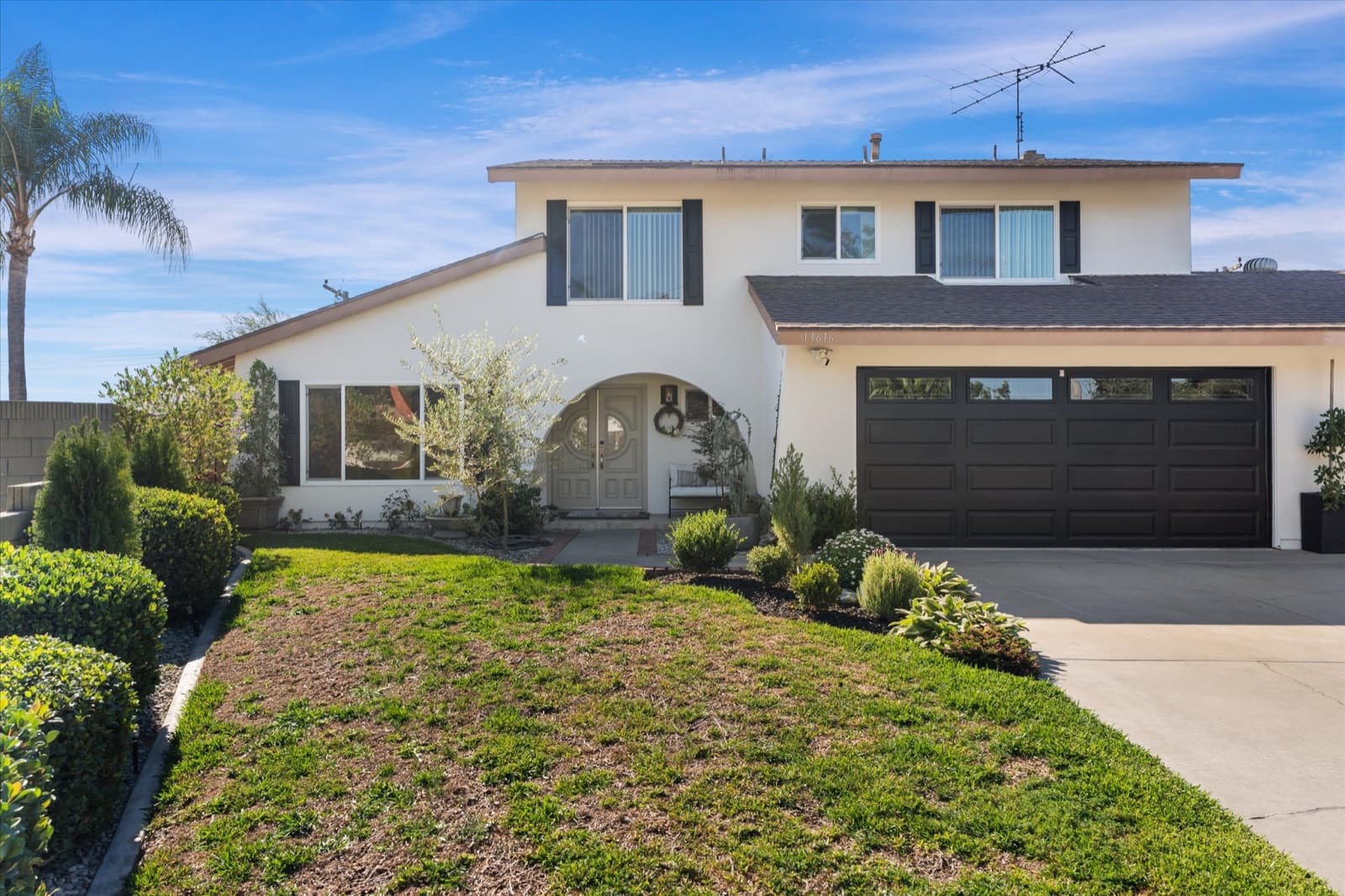 Front exterior of the two-story home at 13616 Ankerton Street in Whittier, with an arched entry, dark garage doors, and a front lawn