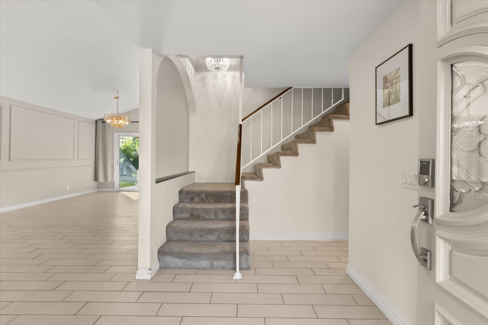 Entry foyer with an arched opening, a carpeted staircase with a white railing, and tile flooring