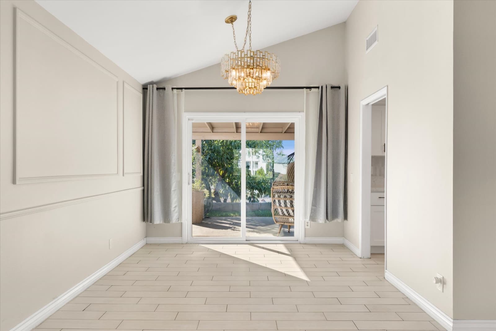 Dining area with a chandelier and sliding glass doors opening toward the covered patio