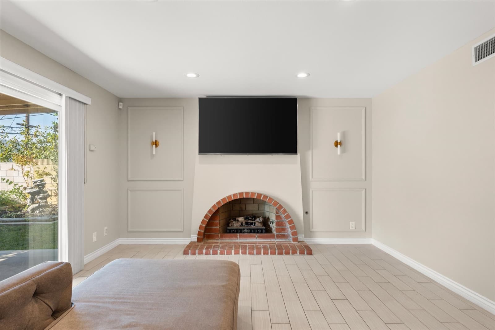 Brick fireplace set into a wall of decorative paneling, with a wall-mounted television above