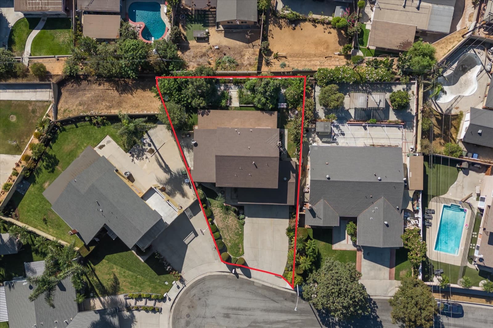Top-down aerial with the property boundaries outlined in red, showing the roof, driveway, and rear yard