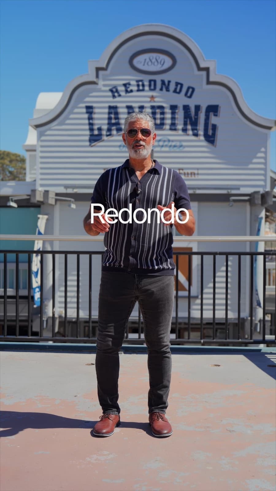 Vertical branding reel thumbnail of an agent at the Redondo Landing pier sign