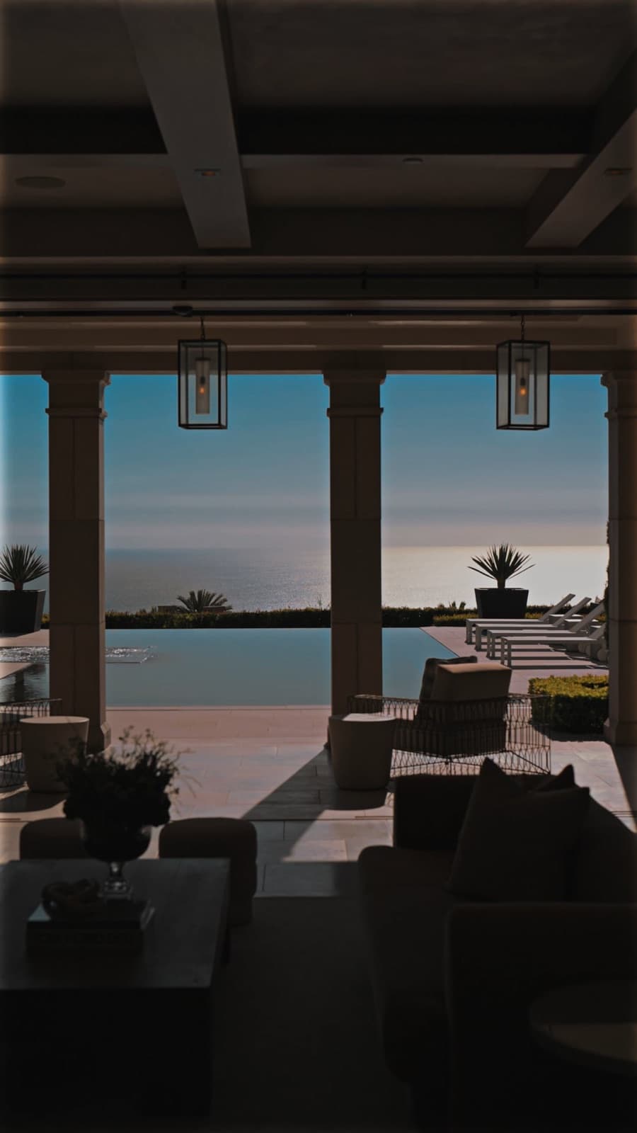 Vertical branding reel thumbnail of a covered patio overlooking an infinity pool and ocean at twilight